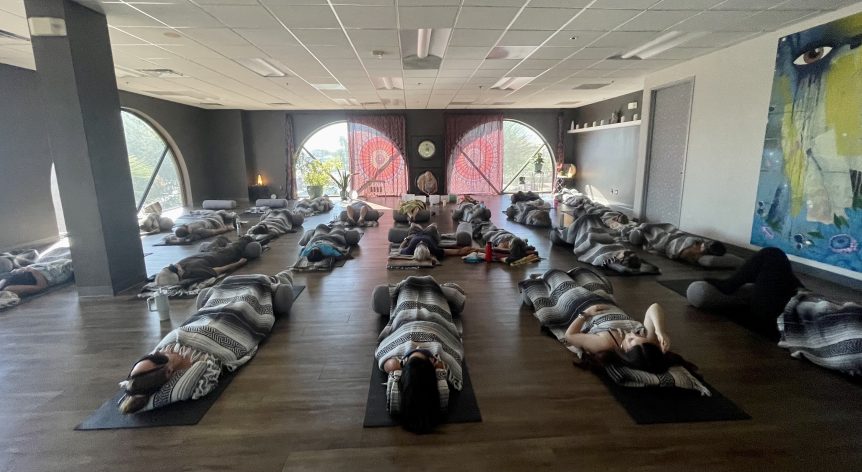 Group of participants laying on mats participating in Breathwork + Sound Healing